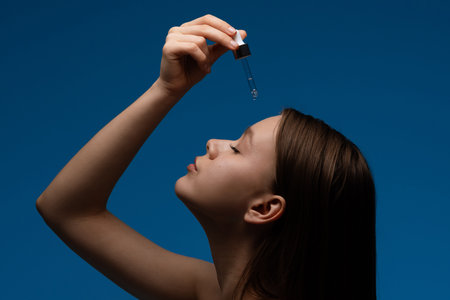 Young Woman Applying Skincare Serum with Dropperの写真素材