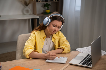 Focused Young Woman Studying with Headphones at Desk