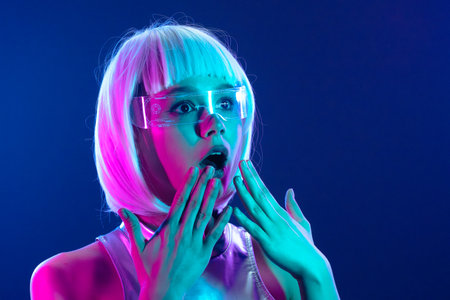 Pleasantly surprised futuristic woman in neon lights with smart glassesの写真素材