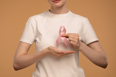 Woman Holding Pink Ribbon Symbolizing Breast Cancer Awarenessの写真素材