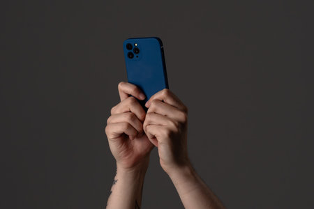 Hands Holding a Modern Smartphone in Dark Background
