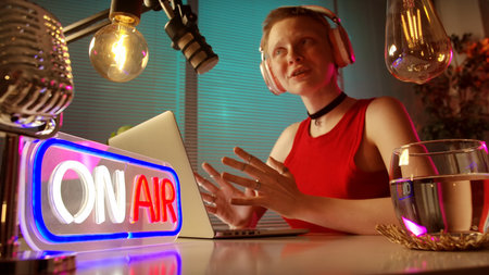 Young Woman Broadcasting a Podcast in a Modern Studio Settingの写真素材