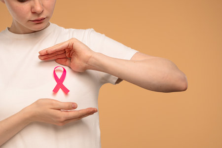 Close-Up of Person Holding Pink Breast Cancer Awareness Ribbonの写真素材