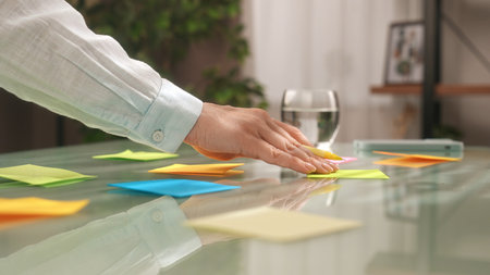 Hands Organizing Colorful Sticky Notes on Table Surfaceの写真素材