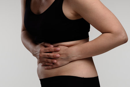 Woman Holding Stomach in Discomfort Due to Pain or Digestive Issueの写真素材
