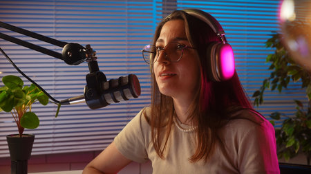 Young Woman Podcasting with Headphones in a Modern Studioの写真素材