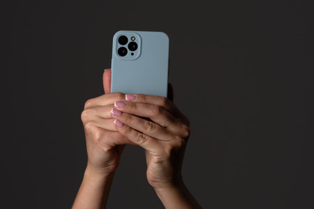 Hands Holding Smartphone Against Dark Background Capturing Moment