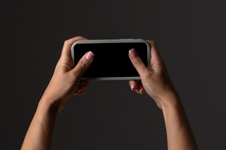 Hands Holding Smartphone for Gaming on Dark Background