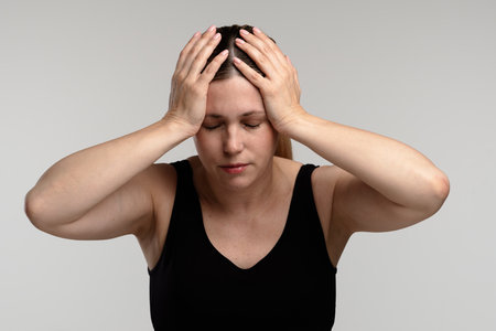 Stressed Woman with Hands on Head in Black Tank Topの写真素材