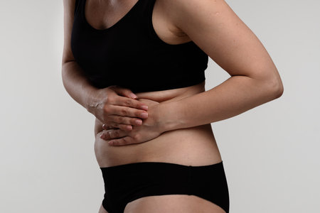 Woman Holding Stomach in Discomfort Due to Painの写真素材