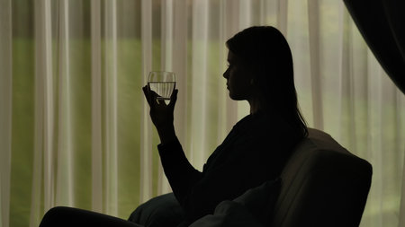 Silhouette of a Woman Relaxing with a Glass in Handの写真素材