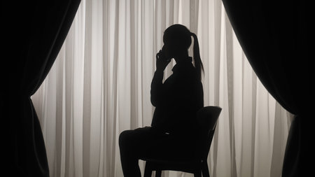 Silhouette of a Person Using Smartphone by Window Curtainsの写真素材
