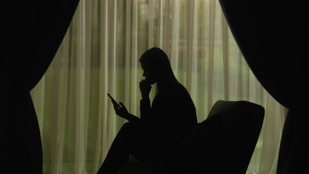 Silhouette of a Woman Using Smartphone by Window