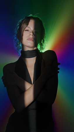 Woman in rainbow spotlight with dramatic contrastの写真素材
