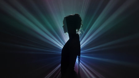 Silhouette of woman in rainbow light burstの写真素材
