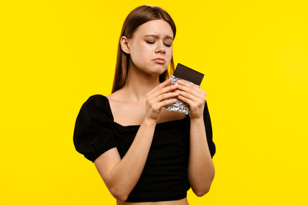 Young Woman Holding Chocolate Bar with Pensive Expressionの写真素材