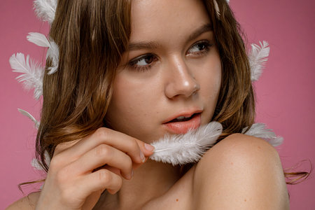 Woman with Feather on Pink Background in Studio Portraitの写真素材