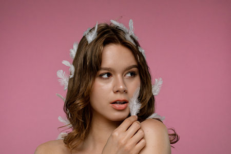 Woman with Feather on Pink Background in Studio Portraitの写真素材