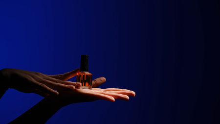 Elegant Display of Nail Polish Bottle Against Deep Blue Backgroundの写真素材