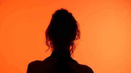 Silhouetted Woman with Orange Background in Minimalist Settingの写真素材