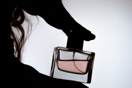 Silhouette of Hand Holding Elegant Glass Perfume Bottleの写真素材