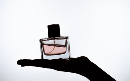 Elegant Fragrance Bottle on Hand Silhouette Background