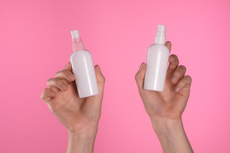 Comparison of Two Cosmetic Bottles in Human Hands Against Pink Background