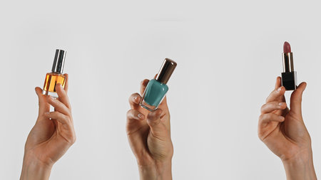 Hand holding various beauty products like nail polish and lipstickの写真素材