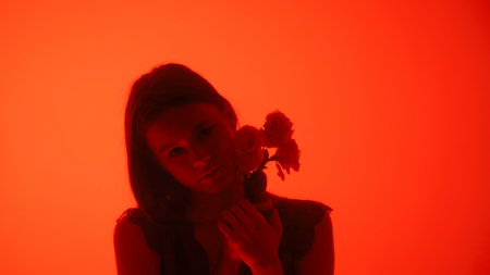 Silhouette of a Woman Holding Flowers in Red Lighting
