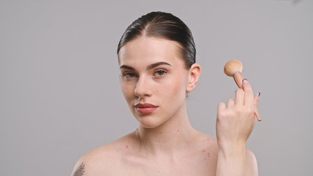 Young Woman Holding Makeup Brush with Confident Expressionの写真素材