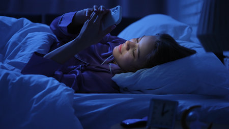 Woman using smartphone in bed during sleepless night