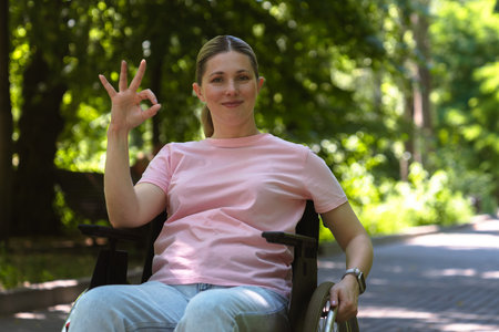 Woman in wheelchair enjoying a sunny day outdoorsの写真素材