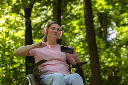 Woman in Pink Shirt Enjoying Music Outdoors While Being in a Wheelchair