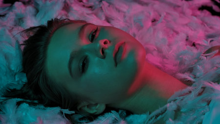 Top shot of woman with feather in neon light on feather background, beauty conceptの写真素材