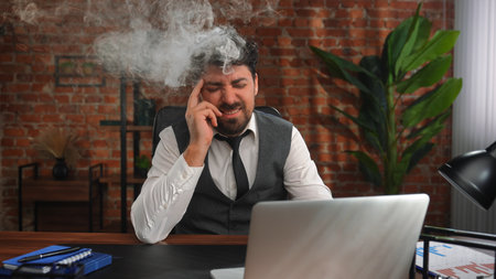 Overwhelmed Businessman Under Stress at Office Deskの写真素材