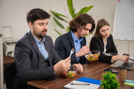 Colleagues Enjoying Healthy Salads During Office Lunch Break Meetingの写真素材