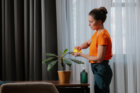 Older Adult Woman Caring for Houseplant with Cloth and Spray Bottle
