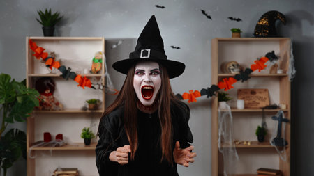 Vampire witch screams in a Halloween decorated room
