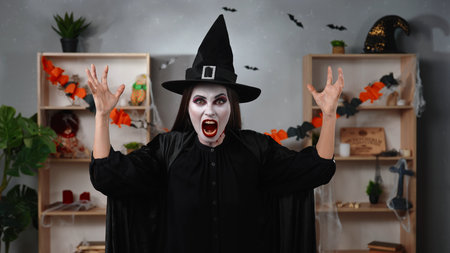 Vampire witch screams in a Halloween decorated roomの写真素材