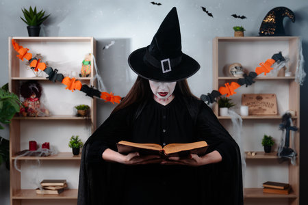 Witch reading an ancient spell book in a Halloween settingの写真素材