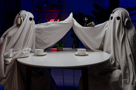 Two funny ghosts record a podcast in a studio with neon lightsの写真素材