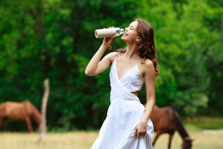 Young Woman Enjoying Summer Outdoors with Drinkの写真素材