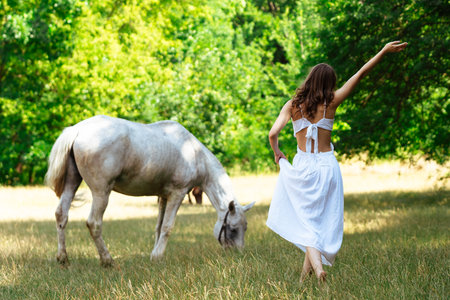 Woman in White Dress with Horse in Green Forest Landscapeの写真素材