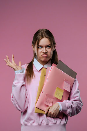 A young female student is upset about her failure, holding folders and notes in her hands.の写真素材