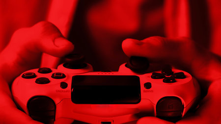 Close up of Gaming Controller Held by Hands with Red Lightingの写真素材