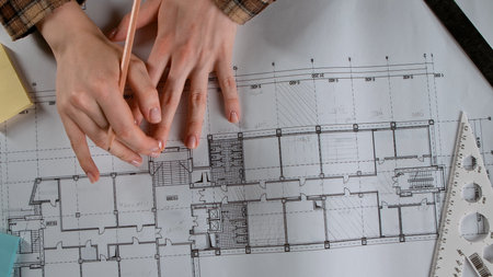 Architectural Drafting on Blueprint with Measuring Tools and Hands