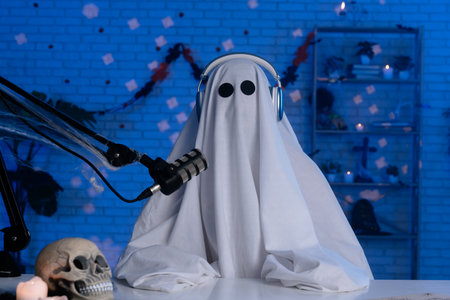 Ghost costume recording podcast or blog in a studio with blue light