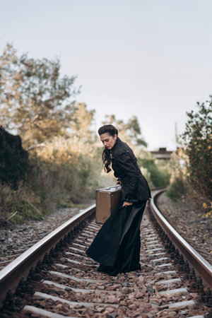 Woman with Vintage Suitcase on Railroad Tracks in Autumn