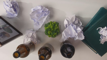 Workspace Chaos with Crumpled Paper and Empty Bottles