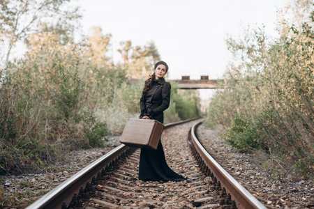 Woman with Vintage Suitcase on Railroad Tracks in Autumnの写真素材